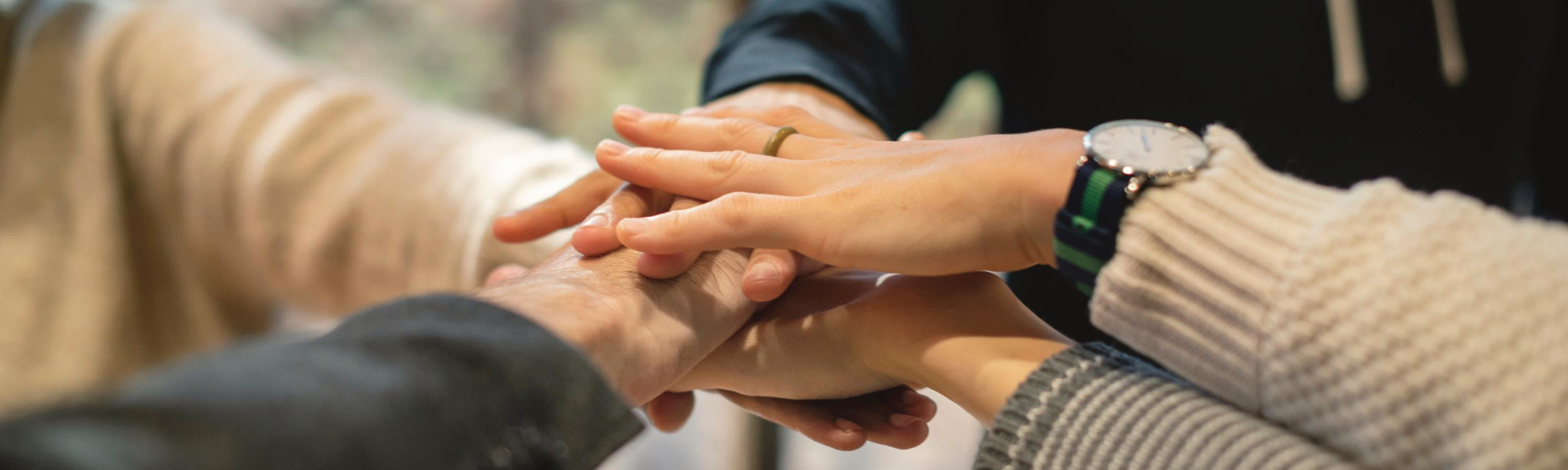 Nahaufnahme von Hände mehrerer Personen, die ein Team-Gefühl vermitteln